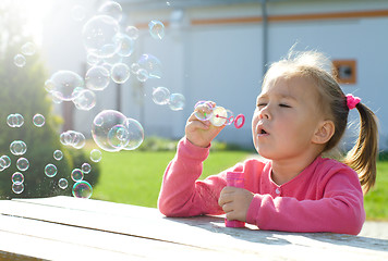 Image showing Little girl is blowing soap bubbles