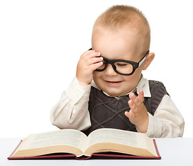 Image showing Little child play with book and glasses