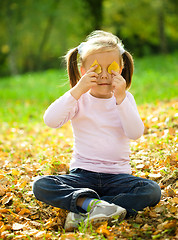 Image showing Little girl is playing in autumn park