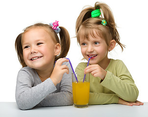 Image showing Two little girls are drinking orange juice