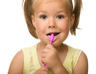 Image showing Little girl is cleaning teeth using toothbrush