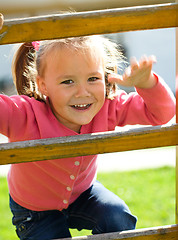 Image showing Cute little girl is climbing up on ladder