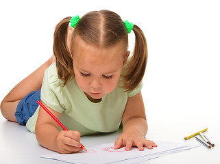 Image showing Little girl is drawing while laying on the floor