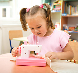 Image showing Little girl is playing with sewing machine