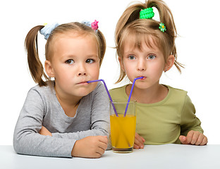 Image showing Two little girls are drinking orange juice