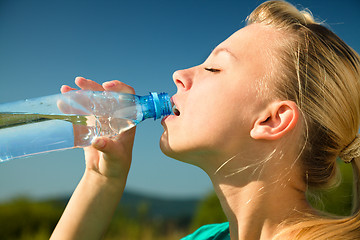 Image showing Young woman is drinking water outdoors