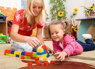 Image showing Teacher and child are playing with bricks