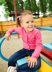 Image showing Cute little girl is riding on merry-go-round