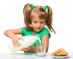 Image showing Cute little girl is pouring milk in glass