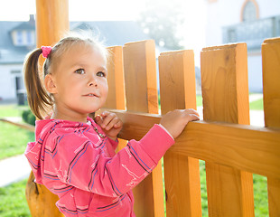 Image showing Cute little girl is standing near a fence