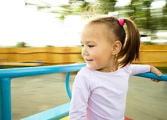 Image showing Cute little girl is riding on merry-go-round