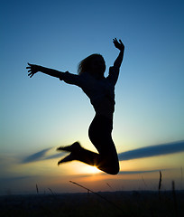 Image showing Silhouette of a girl jumping over sunset