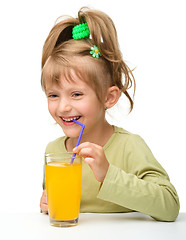 Image showing Cute little girl is drinking orange juice
