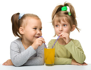 Image showing Two little girls are drinking orange juice