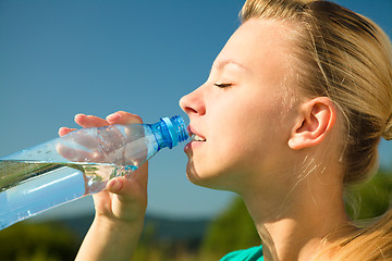 Image showing Young woman is drinking water outdoors