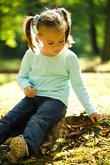 Image showing Little girl is playing in autumn park