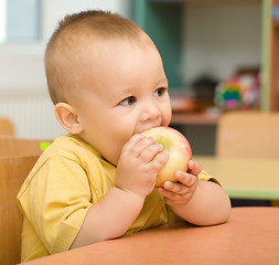 Image showing Little boy is eating apple