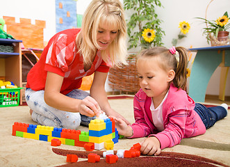 Image showing Teacher and child are playing with bricks