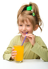 Image showing Cute little girl is drinking orange juice