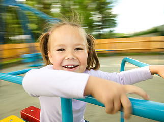 Image showing Cute little girl is riding on merry-go-round