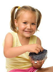 Image showing Cheerful little girl is eating blueberry