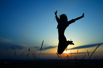 Image showing Silhouette of a girl jumping over sunset