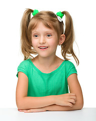 Image showing Little girl is sitting at table in astonishment