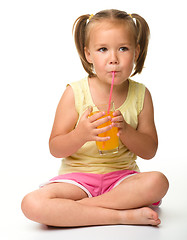 Image showing Little girl drinks orange juice