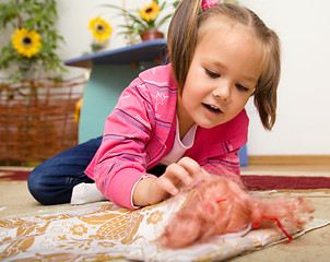 Image showing Little girl is putting her doll to sleep