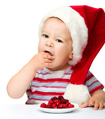 Image showing Cute little boy eating berries wearing santa hat