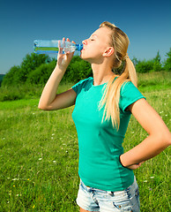 Image showing Young woman is drinking water outdoors