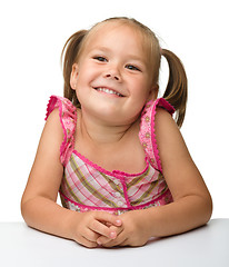 Image showing Happy little girl is sitting at the table