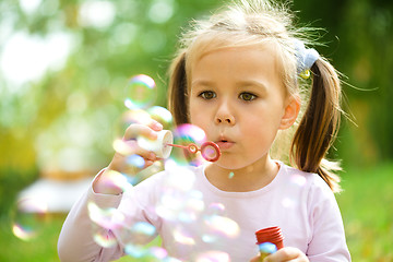 Image showing Little girl is blowing a soap bubbles