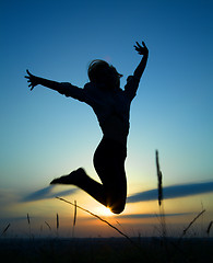 Image showing Silhouette of a girl jumping over sunset