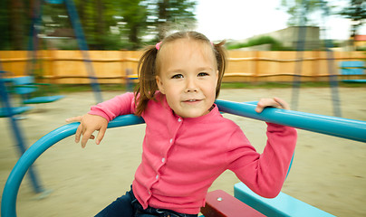 Image showing Cute little girl is riding on merry-go-round