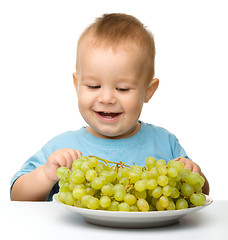 Image showing Little boy is eating grapes