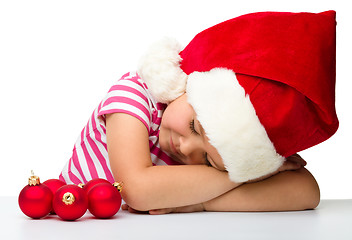 Image showing Cute little girl is sleeping wearing santa hat