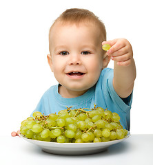 Image showing Little boy is eating grapes