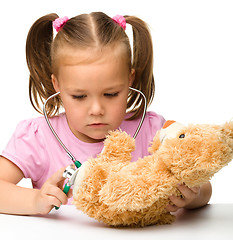 Image showing Little girl is playing with her teddy bear