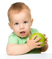 Image showing Little child is eating green apple