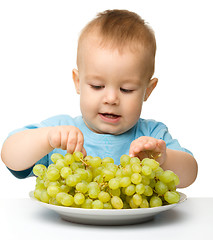 Image showing Little boy is eating grapes