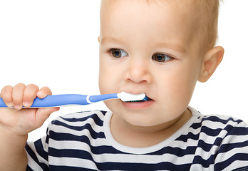Image showing Little boy is cleaning teeth using toothbrush