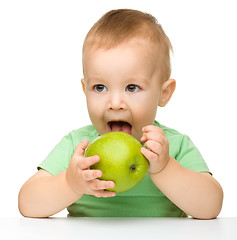 Image showing Little child is eating green apple