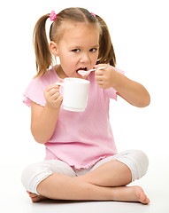 Image showing Cute little girl is eating yogurt