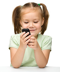 Image showing Cute little girl is playing with cell phone