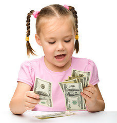 Image showing Cute little girl is counting dollars