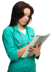 Image showing Young attractive woman doctor is writing