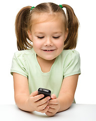 Image showing Cute little girl is playing with cell phone