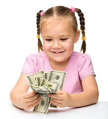 Image showing Cute little girl is counting dollars