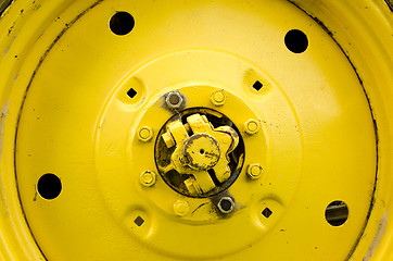 Image showing Yellow tractor wheel closeup details bolt nut hole 